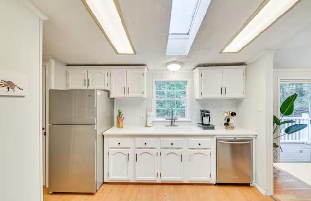 kitchen with a sink, white cabinets, plenty of natural light, and stainless steel appliances