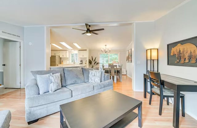 living room featuring light wood-type flooring and ceiling fan with notable chandelier