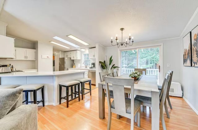 dining room featuring light wood-type flooring, a notable chandelier, and vaulted ceiling