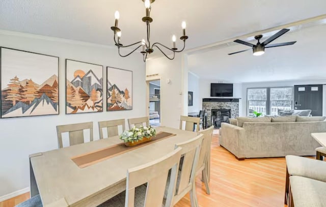 dining area featuring light wood-style floors, a fireplace, and ceiling fan with notable chandelier