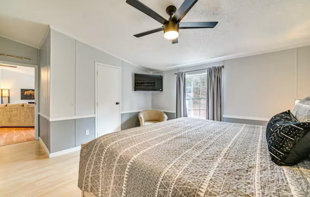 bedroom with ceiling fan, a textured ceiling, wood finished floors, lofted ceiling, and baseboards