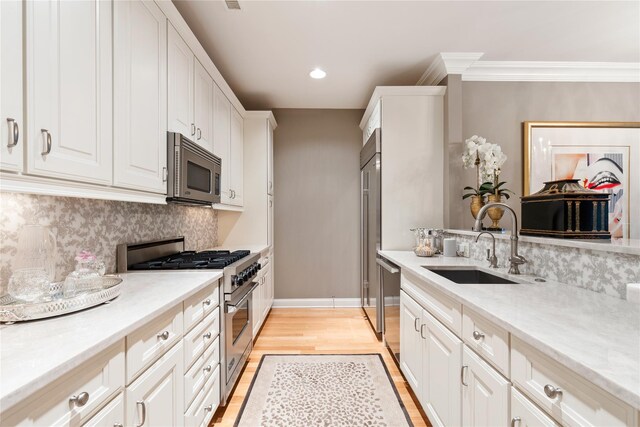 1 Christie Pl Unit 205W, Scarsdale, NY 10583 - kitchen featuring a sink, stainless steel appliances, light wood-type flooring, backsplash, and white cabinetry