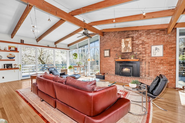living room featuring a ceiling fan, hardwood / wood-style floors, vaulted ceiling with beams, and a fireplace