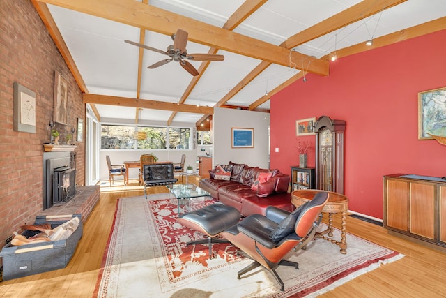living area with a wood stove, beam ceiling, brick wall, light wood finished floors, and high vaulted ceiling
