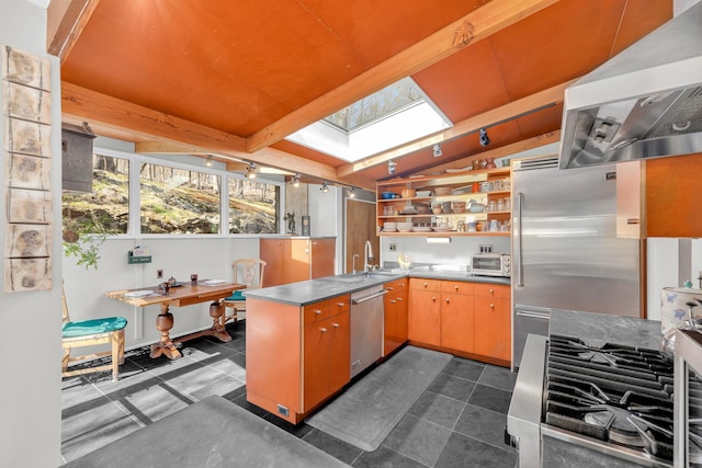 kitchen featuring stainless steel countertops, stainless steel appliances, open shelves, rail lighting, and wall chimney exhaust hood