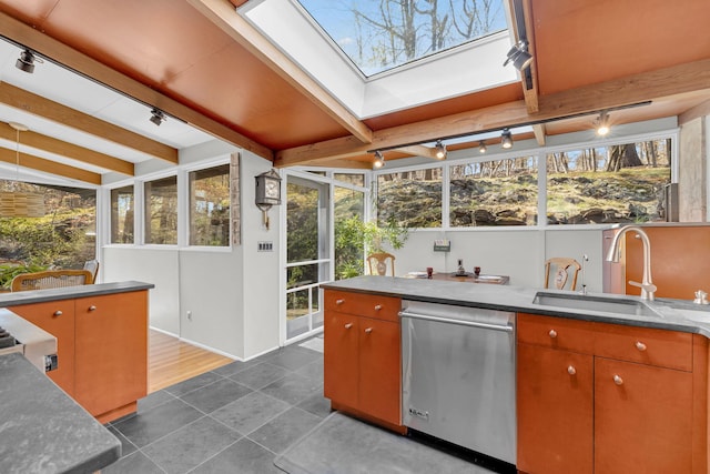 kitchen with track lighting, stainless steel dishwasher, dark tile patterned floors, and a sink