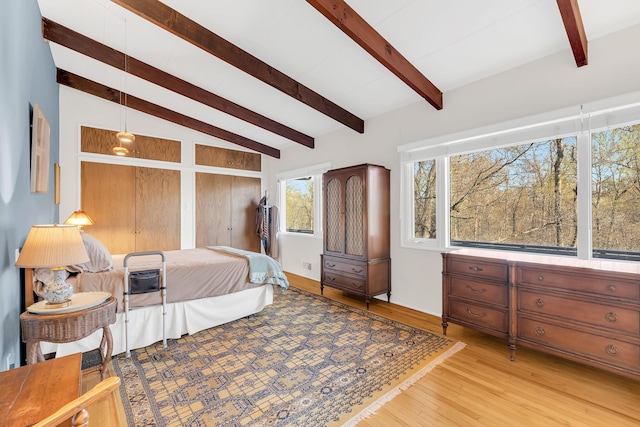 bedroom with light wood-type flooring and vaulted ceiling with beams