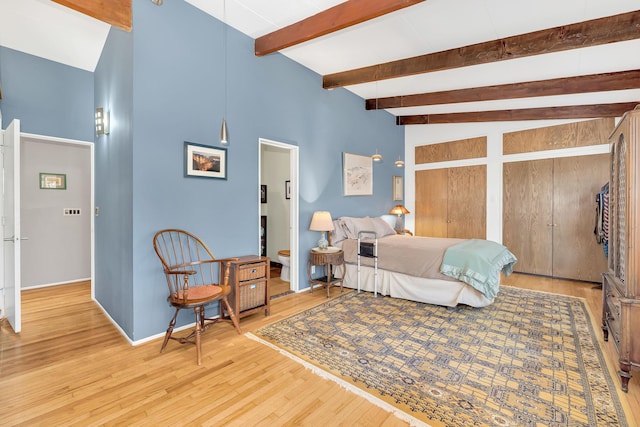 bedroom with beamed ceiling, wood finished floors, and baseboards