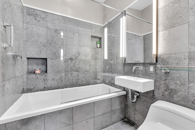 bathroom featuring tile walls, tiled shower / bath combo, toilet, and a sink
