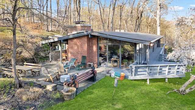 back of property with a patio, brick siding, a yard, a chimney, and a deck