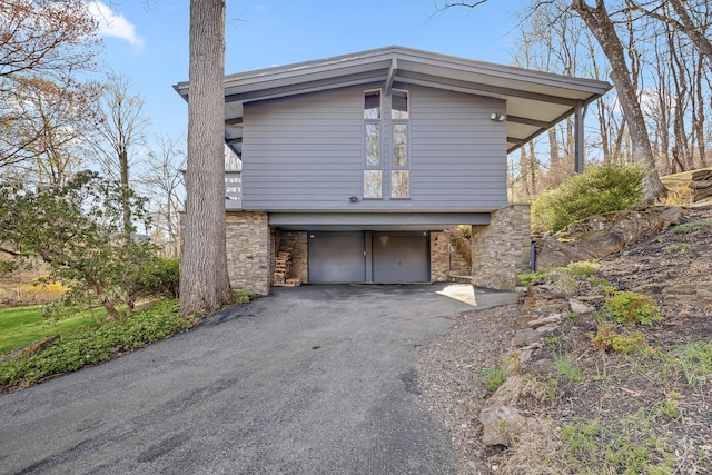 view of home's exterior featuring driveway, stone siding, and an attached garage