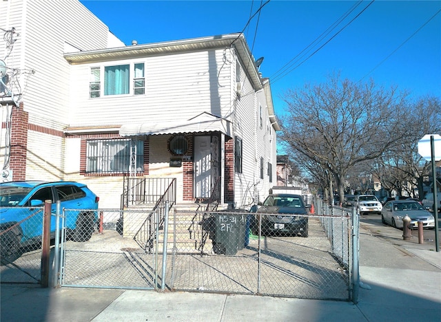 multi unit property with a gate, brick siding, and a fenced front yard