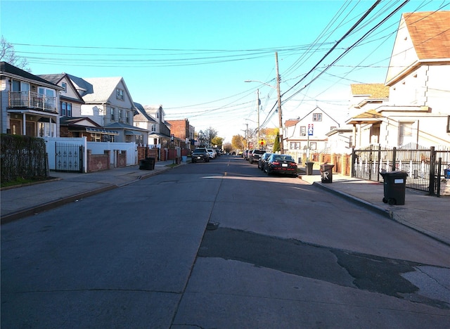 view of road featuring a residential view, sidewalks, curbs, and street lighting