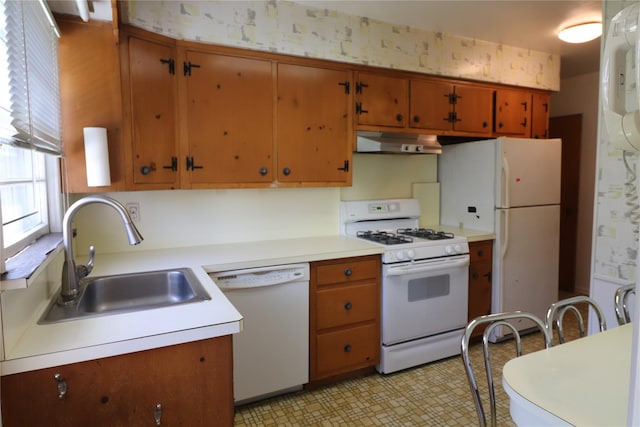 kitchen featuring light countertops, a sink, under cabinet range hood, and white appliances