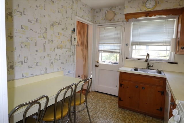 kitchen featuring stove, a sink, wallpapered walls, and light countertops