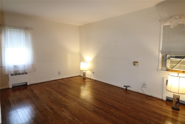 unfurnished room with baseboards, cooling unit, radiator heating unit, and hardwood / wood-style flooring