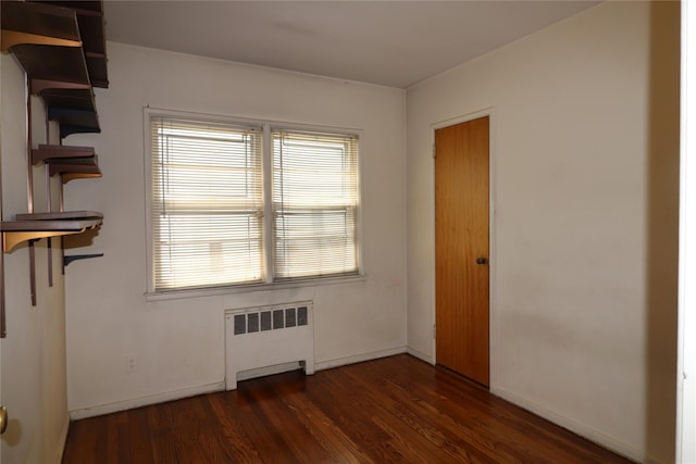 empty room featuring baseboards, radiator heating unit, wood finished floors, and plenty of natural light