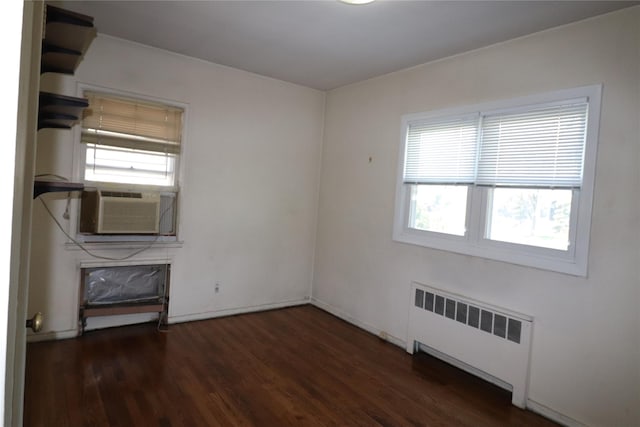 interior space with radiator heating unit, a wealth of natural light, cooling unit, and wood finished floors