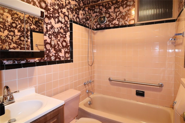 bathroom with wallpapered walls, shower / bathtub combination, toilet, vanity, and tile walls