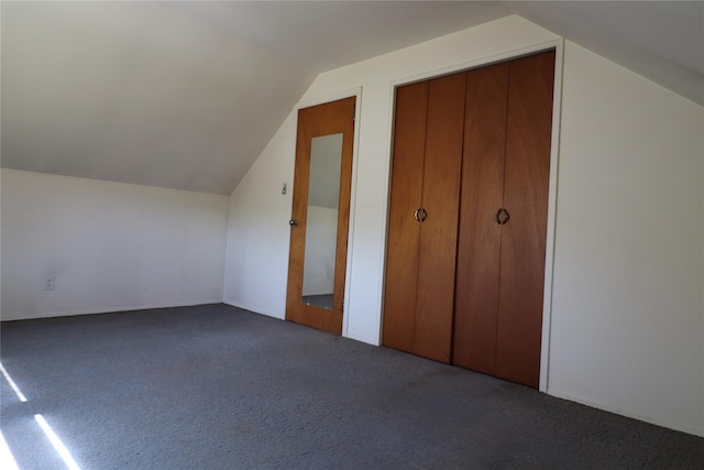 additional living space with vaulted ceiling and dark colored carpet