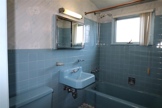 full bath with toilet, a sink, shower / bath combination, and tile walls