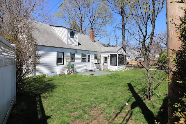 back of property with roof with shingles, a chimney, a patio area, a yard, and a sunroom