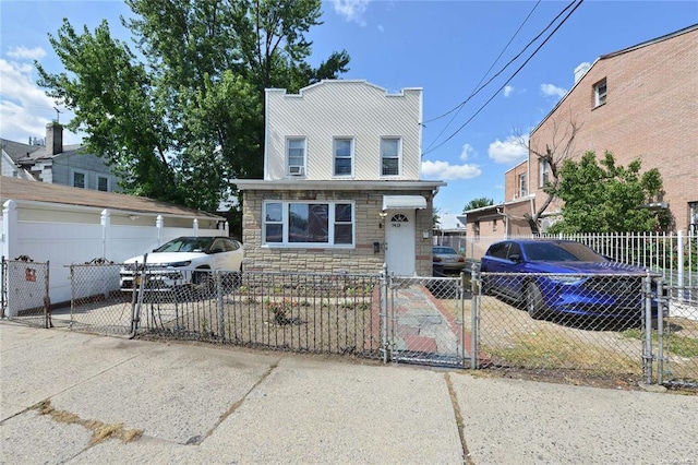 view of front facade with stone siding, a gate, and a fenced front yard