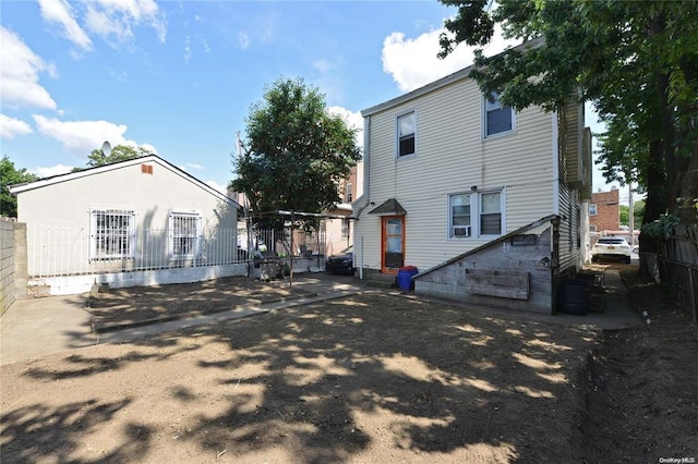 rear view of property featuring entry steps and fence