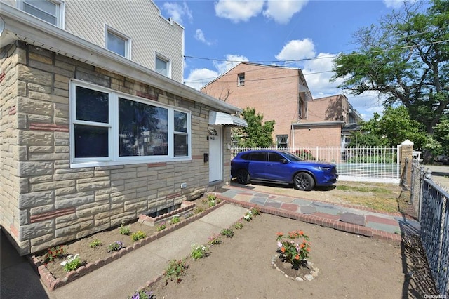 view of home's exterior featuring stone siding and fence