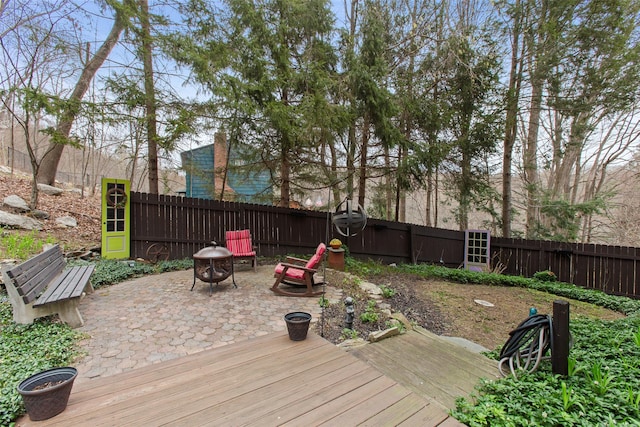 deck with a patio area, a fenced backyard, and a fire pit