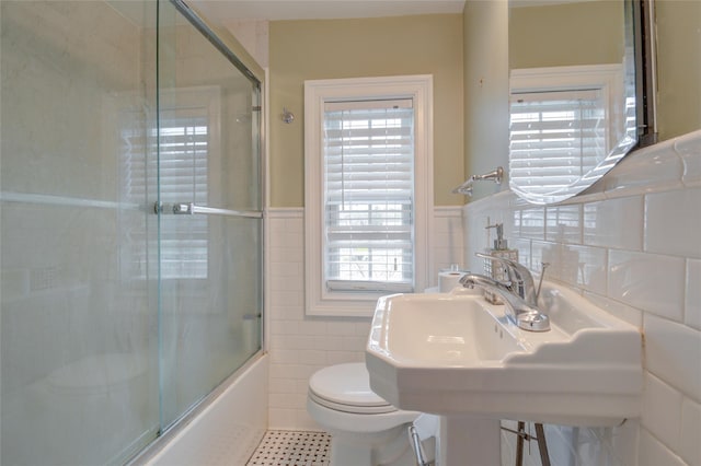 163 N Hamilton St, Poughkeepsie, NY 12601 - bathroom featuring tile patterned floors, toilet, tile walls, bath / shower combo with glass door, and wainscoting
