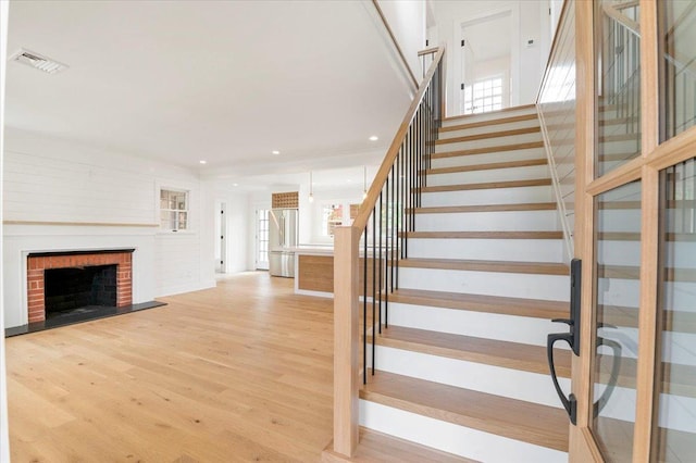 1000 Washington Dr, Centerport, NY 11721 - stairs featuring wood finished floors, a fireplace, and recessed lighting