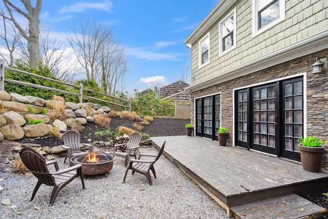 view of patio with a fire pit, fence, and a deck