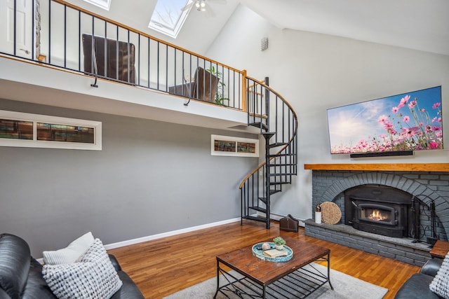 living room with stairway, a skylight, high vaulted ceiling, and wood finished floors