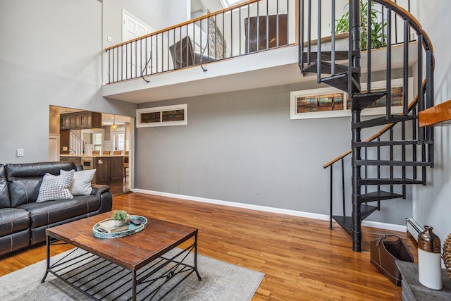 living area featuring stairway, a high ceiling, and baseboards