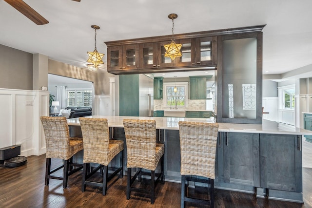 interior space featuring a decorative wall, dark wood-style flooring, a sink, and pendant lighting
