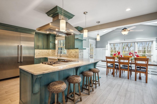kitchen with cooktop, light wood finished floors, built in refrigerator, green cabinets, and a peninsula