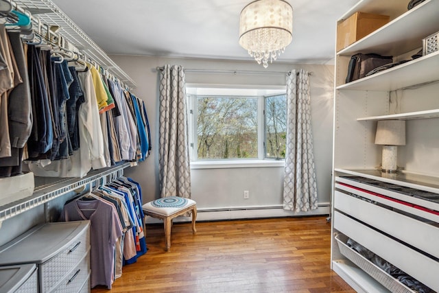 walk in closet featuring light wood-style flooring, a chandelier, and a baseboard radiator