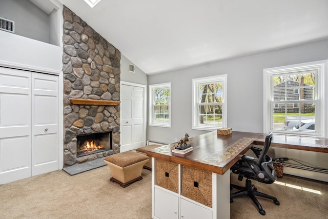 office with light carpet, a stone fireplace, visible vents, and a wealth of natural light