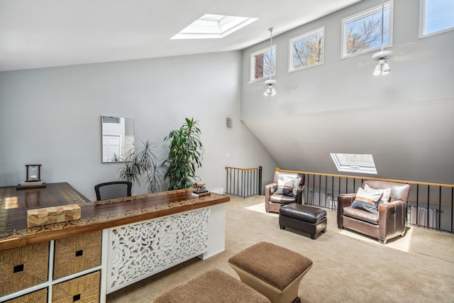 carpeted office space with ceiling fan and vaulted ceiling with skylight