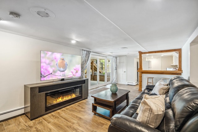 living area with baseboard heating, baseboards, a glass covered fireplace, and light wood-style flooring