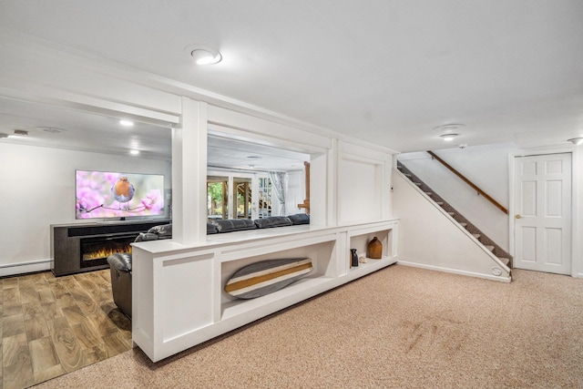 living room with a baseboard radiator, a lit fireplace, and stairs