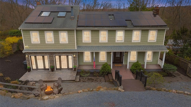 townhome / multi-family property with a chimney, a fenced backyard, solar panels, an attached garage, and an outdoor fire pit