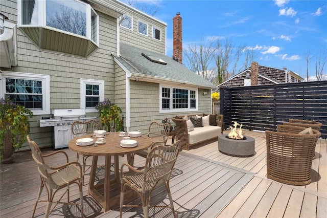 wooden terrace with grilling area, outdoor dining space, and an outdoor fire pit