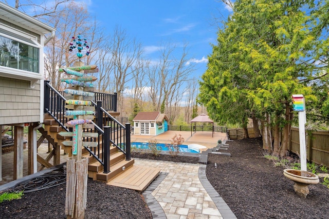 view of yard featuring a fenced in pool, stairs, a fenced backyard, a patio area, and an outdoor structure