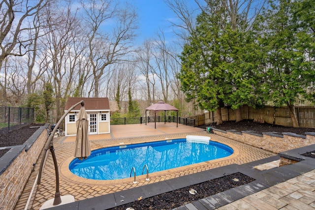 view of pool with a fenced backyard, an outbuilding, a fenced in pool, and a storage structure
