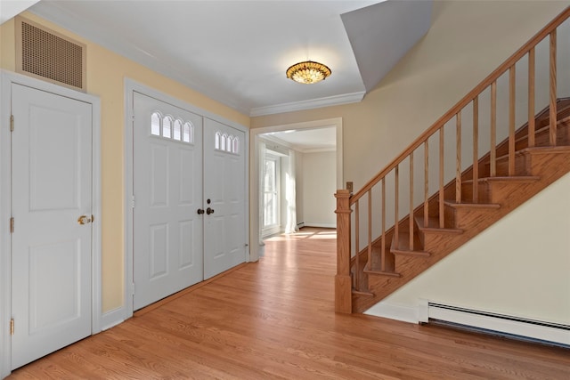 entrance foyer featuring a baseboard radiator, crown molding, wood finished floors, stairs, and visible vents