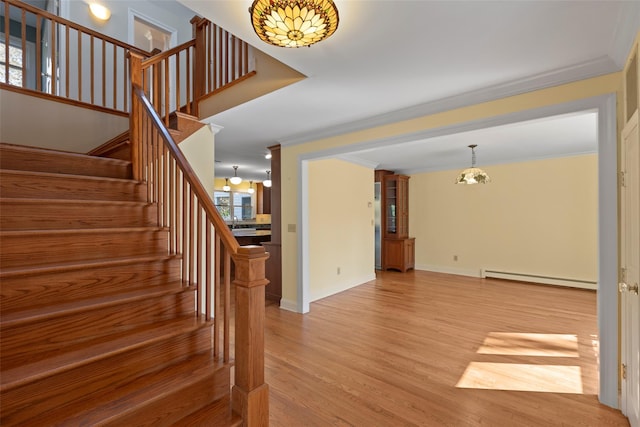 stairs featuring baseboards, baseboard heating, wood finished floors, and ornamental molding