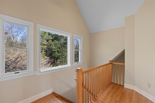 stairway featuring vaulted ceiling, wood finished floors, and baseboards