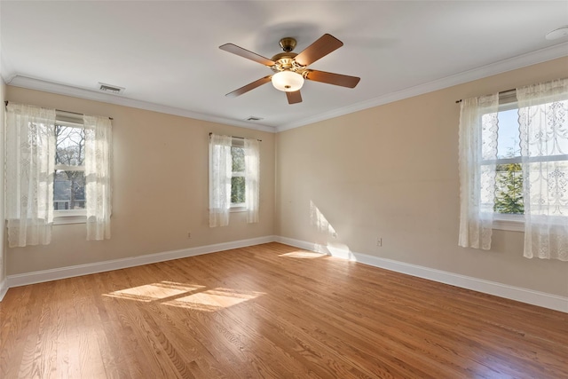 unfurnished room featuring plenty of natural light, light wood-style flooring, visible vents, and crown molding